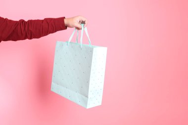 Resmi ve sıradan kırmızı tişörtlü Asyalı kıdemli bir adam. Elinde açık mavi polkadot çantasıyla pembe arka planda izole edilmiş..