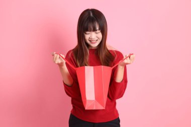 Çin Yeni Yılı, kırmızı günlük tişörtlü Asyalı kadın, el ele tutuşan el çantası ve sürpriz, vay canına ve pembe arka planda izole edilmiş etkileyici bir şekilde. Gen Z