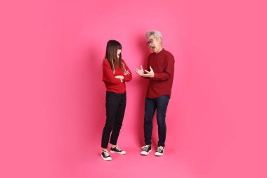 Çin Yeni Yılı, Asyalı son sınıf öğrencisi erkek ve kadın Noel Baba şapkası giyer, günlük kırmızı kıyafetler giyer ve pembe arka planda münakaşa eder..