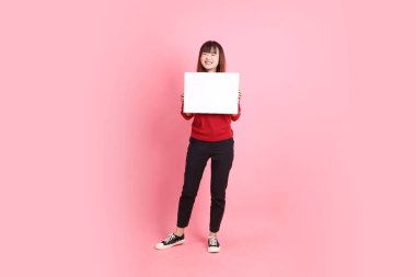 Çin Yeni Yılı, pembe arka planda boş tuval tutan kırmızı, sıradan tişörtlü Asyalı bir kadın. Gen Z