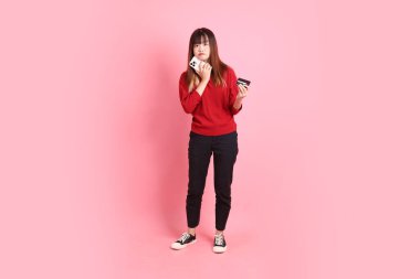 Mutlu Çin Yeni Yılı, pembe arka planda izole edilmiş cep telefonu kartı tutan kırmızı günlük Asyalı kadın tişörtü. Gen Z