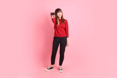 Mutlu Çin Yeni Yılı, pembe arka planda el ele tutuşan kırmızı, sıradan tişörtlü, Asyalı bir kadın. Gen Z