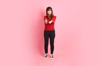 Mutlu Çin Yeni Yılı, pembe arka planda el ele tutuşan kırmızı, sıradan tişörtlü, Asyalı bir kadın. Gen Z