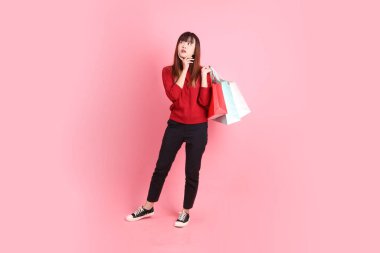 Mutlu Çin Yeni Yılı, pembe arka planda izole edilmiş, el ele tutuşan, el ele tutuşan, kırmızı günlük Asyalı kadın tişörtü. Gen Z