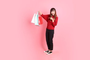 Mutlu Çin Yeni Yılı, pembe arka planda izole edilmiş, el ele tutuşan, kırmızı, sıradan tişörtlü, Asyalı bir kadın. Gen Z