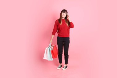 Mutlu Çin Yeni Yılı, pembe arka planda izole edilmiş, el ele tutuşan, kırmızı, sıradan tişörtlü, Asyalı bir kadın. Gen Z