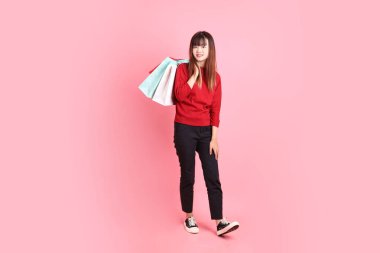 Mutlu Çin Yeni Yılı, pembe arka planda izole edilmiş el ele tutuşan kırmızı tişörtlü Asyalı kadın. Gen Z