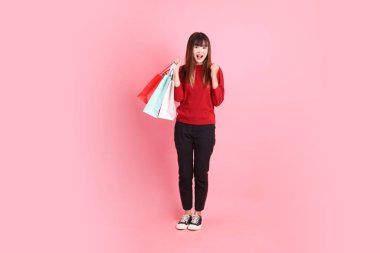 Mutlu Çin Yeni Yılı, kırmızı günlük tişörtlü, el ele tutuşan, heyecanlı, pembe arka planda izole edilmiş genç Asyalı kadın. Gen Z