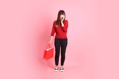 Mutlu Çin Yeni Yılı, kırmızı günlük tişörtlü, el ele tutuşan Asyalı bir kadın, sürpriz, pembe arka planda izole edilmiş. Gen Z