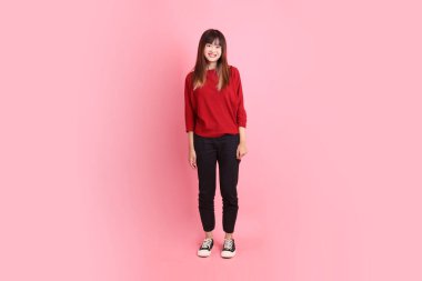 Mutlu Çin Yeni Yılı, pembe arka planda duran ve gülümseyen kırmızı günlük tişörtlü Asyalı genç bayan. Gen Z