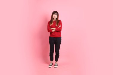 Mutlu Çin Yeni Yılı, kırmızı günlük tişörtlü Asyalı kadın ciddi bir jest, pembe arka planda izole edilmiş bir kol. Gen Z