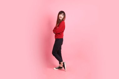 Mutlu Çin Yeni Yılı, kırmızı günlük tişörtlü Asyalı kadın ciddi bir jest, pembe arka planda izole edilmiş bir kol. Gen Z