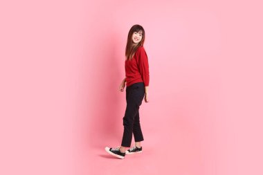 Mutlu Çin Yeni Yılı, pembe arka planda duran ve gülümseyen kırmızı günlük tişörtlü Asyalı genç bayan. Gen Z