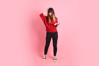 Mutlu Çin Yeni Yılı, kırmızı günlük tişörtlü Asyalı genç bayan kontrolör jesti ya da pembe arka planda izole video oyun konsolu oynuyor. Gen Z