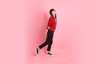 Mutlu Çin Yeni Yılı, pembe arka planda duran ve gülümseyen kırmızı günlük tişörtlü Asyalı genç bayan. Gen Z