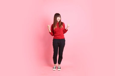 Mutlu Çin Yeni Yılı, kırmızı günlük tişörtlü Asyalı kadın evet jesti, heyecanlı, pembe arka planda izole edilmiş kutlamayı kutluyor. Gen Z