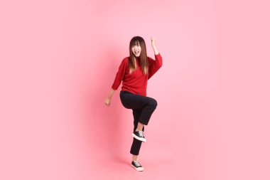 Mutlu Çin Yeni Yılı, kırmızı günlük tişörtlü Asyalı kadın evet jesti, heyecanlı, pembe arka planda izole edilmiş kutlamayı kutluyor. Gen Z