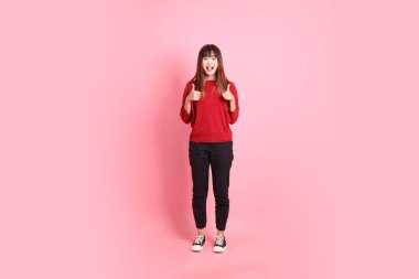 Mutlu Çin Yeni Yılı, kırmızı günlük tişörtlü Asyalı genç bayan baş parmak işareti ile, tamam ya da pembe arka planda izole edilmiş. Gen Z