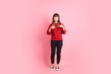 Mutlu Çin Yeni Yılı, kırmızı günlük tişörtlü Asyalı genç bayan baş parmak işareti ile, tamam ya da pembe arka planda izole edilmiş. Gen Z