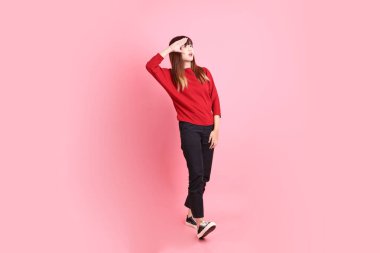 Happy Chinese New Year, young  female asian woman in red casual t-shirt with gesture of Walking isolated on the pink background. Gen Z clipart