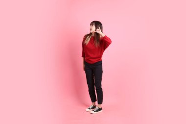 Mutlu Çin Yeni Yılı, pembe arka planda izole edilmiş, kırmızı günlük tişörtlü Asyalı genç bayan. Gen Z