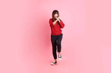 Mutlu Çin Yeni Yılı, pembe arka planda izole edilmiş kırmızı günlük tişörtlü Asyalı genç bayan dövüşme jesti. Gen Z