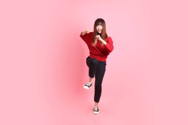 Mutlu Çin Yeni Yılı, pembe arka planda izole edilmiş kırmızı günlük tişörtlü Asyalı genç bayan dövüşme jesti. Gen Z