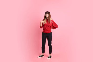 Mutlu Çin Yeni Yılı, kırmızı günlük tişörtlü Asyalı genç bayan pembe arka planda kendini izole edilmiş hisseden jestler. Gen Z