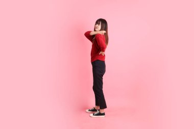 Mutlu Çin Yeni Yılı, pembe arka planda izole edilmiş sırt ağrısı jesti ile kırmızı günlük Asyalı kadın tişörtü. Gen Z