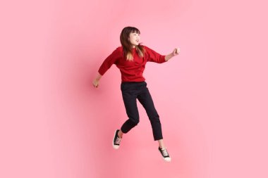 Mutlu Çin Yeni Yılı, pembe arka planda izole edilmiş kırmızı günlük tişörtlü genç Asyalı kadın. Gen Z