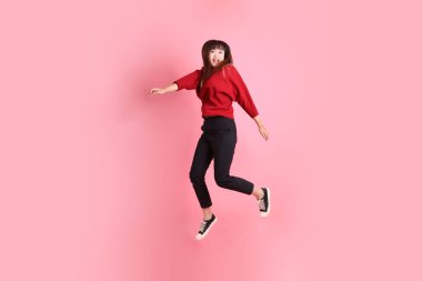 Mutlu Çin Yeni Yılı, kırmızı günlük tişörtlü Asyalı kadın evet jesti, heyecanlı, pembe arka planda izole edilmiş kutlamayı kutluyor. Gen Z