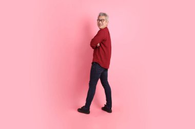 Mutlu Çin Yeni Yılı, resmi ve sıradan kırmızı gömlekli Asyalı son sınıf öğrencisi. Ciddi bir jestle pembe arka planda izole edilmiş bir şekilde kollarını kavuşturdu..