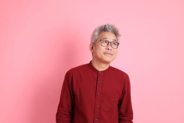 Mutlu Çin Yeni Yılı, resmi ve sıradan kırmızı tişörtlü Asyalı son sınıf öğrencisi pembe arka planda beklemede ve gülümsüyor..