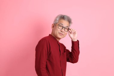 Mutlu Çin Yeni Yılı, resmi ve sıradan kırmızı tişörtlü Asyalı son sınıf öğrencisi pembe arka planda beklemede ve gülümsüyor..