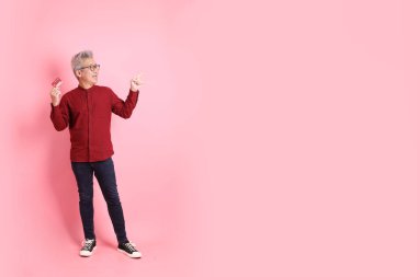 Mutlu Çin Yeni Yılı, resmi ve sıradan kırmızı tişörtlü Asyalı son sınıf öğrencisi pembe arka planda izole edilmiş kredi kartı taşıyor..