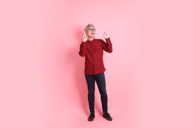 Mutlu Çin Yeni Yılı, resmi ve sıradan kırmızı tişörtlü Asyalı son sınıf öğrencisi pembe arka planda izole edilmiş bir jestle.