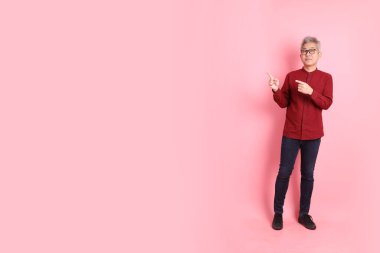 Mutlu Çin Yeni Yılı, resmi ve sıradan kırmızı tişörtlü Asyalı son sınıf öğrencisi pembe arka planda izole edilmiş bir jestle.