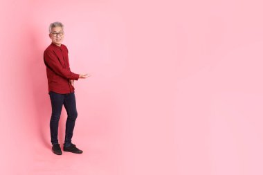 Mutlu Çin Yeni Yılı, resmi ve sıradan kırmızı tişörtlü Asyalı son sınıf öğrencisi pembe arka planda izole edilmiş bir jestle.