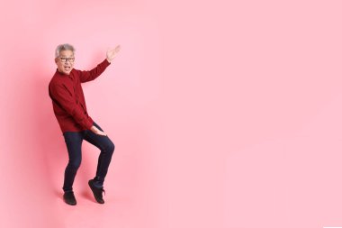 Mutlu Çin Yeni Yılı, resmi ve sıradan kırmızı tişörtlü Asyalı son sınıf öğrencisi pembe arka planda izole edilmiş bir jestle.