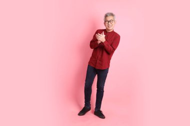 Mutlu Çin Yeni Yılı, resmi ve sıradan kırmızı tişörtlü Asyalı son sınıf öğrencisi pembe arka planda el çırpma hareketi yapıyor..