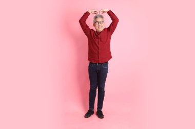 Mutlu Çin Yeni Yılı, resmi ve sıradan kırmızı tişörtlü Asyalı son sınıf öğrencisi. Kalp şeklinde jestler, mini kalp, pembe arka planda izole edilmiş aşk..