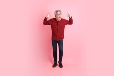 Mutlu Çin Yeni Yılı, resmi ve sıradan kırmızı tişörtlü Asyalı son sınıf öğrencisi pembe arka planda izole edilmiş öfkeli ve çığlıklar atan biri..