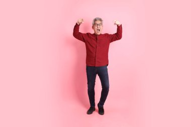 Mutlu Çin Yeni Yılı, resmi ve sıradan kırmızı tişörtlü Asyalı son sınıf öğrencisi pembe arka planda izole edilmiş öfkeli ve çığlıklar atan biri..