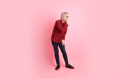 Mutlu Çin Yeni Yılı, resmi ve sıradan kırmızı tişörtlü Asyalı son sınıf öğrencisi pembe arka planda izole edilmiş konuşma ya da fısıltıyla.