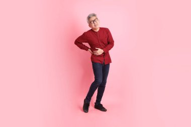 Mutlu Çin Yeni Yılı, resmi ve sıradan kırmızı tişörtlü Asyalı son sınıf öğrencisi pembe arka planda izole edilmiş sırt ağrısı jesti ile.