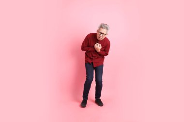 Mutlu Çin Yeni Yılı, resmi ve sıradan kırmızı tişörtlü Asyalı son sınıf öğrencisi pembe arka planda izole edilmiş Heartache jesti.