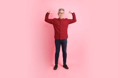 Mutlu Çin Yeni Yılı, resmi ve sıradan kırmızı tişörtlü Asyalı son sınıf öğrencisi. Sağlıklı, güçlü, pembe arka planda izole edilmiş bir jestle..