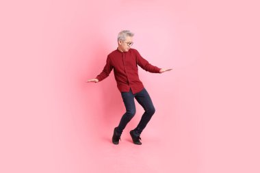 Mutlu Çin Yeni Yılı, resmi ve sıradan kırmızı tişörtlü Asyalı kıdemli dinamik duruşu olan, pembe arka planda izole edilmiş bacağını tekmelerken bağıran adam..