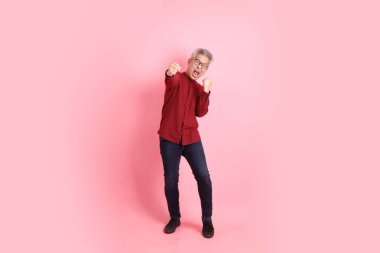 Mutlu Çin Yeni Yılı, resmi ve sıradan kırmızı tişörtlü Asyalı son sınıf öğrencisi pembe arka planda izole edilmiş savaş jestleriyle.