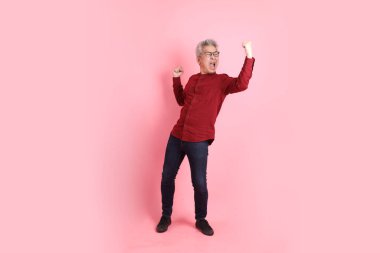 Mutlu Çin Yeni Yılı, resmi ve sıradan kırmızı tişörtlü Asyalı son sınıf öğrencisi pembe arka planda izole edilmiş savaş jestleriyle.